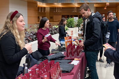 Booth staff at a table at an event giving students information