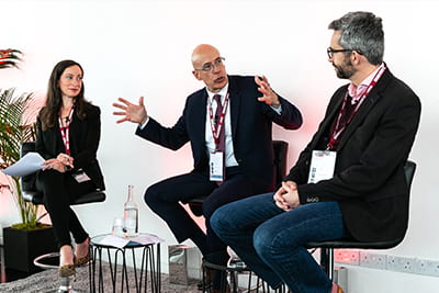 Person talking and gesturing in a three-person event panel